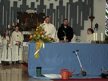 Die Angelausrüstung (rechts am Altar) und die Symbole der Fürbitten, die in der Kirche gesammelt wurden, finden sich vor dem Altar beim Familiengottesdienst in der Pfarrei Heilig-Geist in Ludwigsstadt; hinter dem Altar steht Pastoralreferent Grünbeck mit den Ministranten. Foto: Büttner