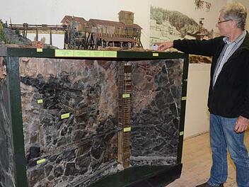 Günther Scheler erörtert ein Modell, von Hubert Busse gebaut, das die St. Katharinazeche in Stockheim mit dem Aufbau und Förderturm im Jahr 1957, sowie die Gesteinsschichten, Schächte und Stollen unter Tage darstellt. Foto: K-H. Hofmann