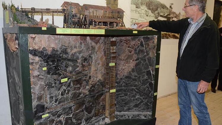 Günther Scheler erörtert ein Modell, von Hubert Busse gebaut, das die St. Katharinazeche in Stockheim mit dem Aufbau und Förderturm im Jahr 1957, sowie die Gesteinsschichten, Schächte und Stollen unter Tage darstellt. Foto: K-H. Hofmann