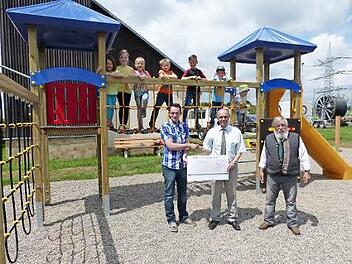 Stellvertretend für die drei Neuensorger Vereine übergaben Michael Kühnel (vorne, links) und Bruno Tittel (vorne, rechts) auf dem Spielareal die 1000 Euro an Bürgermeister Franz Uome. Auf dem neuen Kletterturm einige Neuensorger Kinder.  Foto: Klaus-Peter Wulf