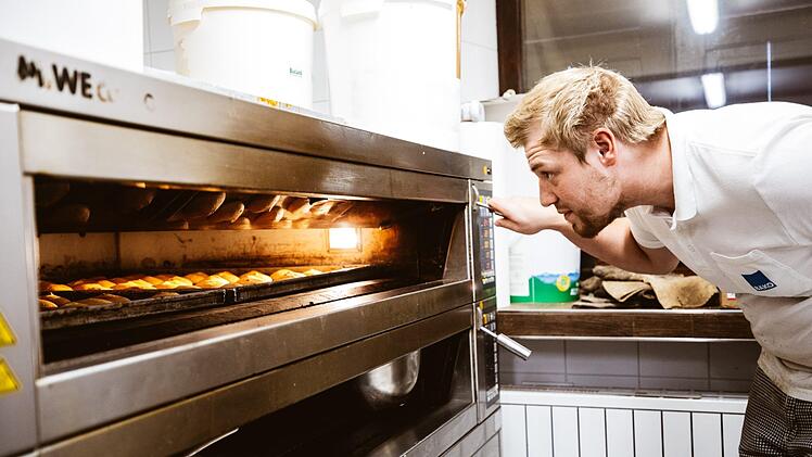 Der perfekte Zeitpunkt: Nach einer Viertelstunde wirft Sebastian Zeis einen ersten prüfenden Blick auf die Rohlinge. Haben sie die erwünschte goldgelbe Farbe, dürfen sie den Ofen verlassen. Foto: Marian Hamacher
