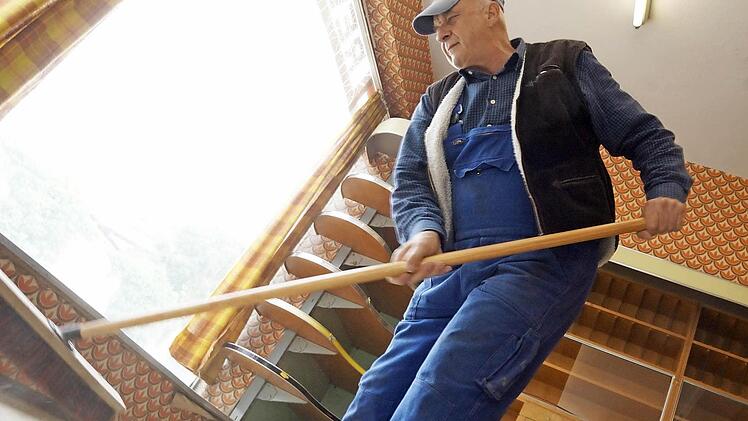 Erich Schmitt fegt den Einkaufsraum aus.