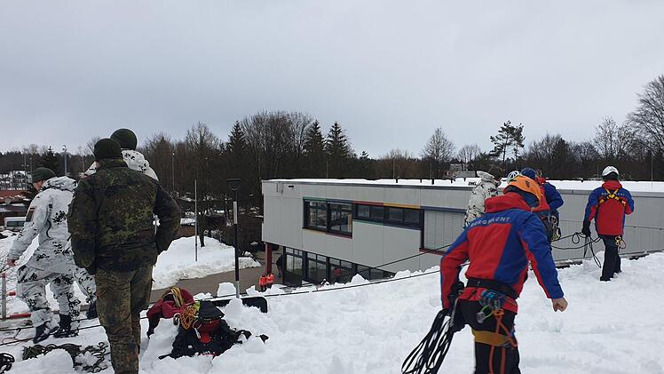 Gemeinsam mit einer Gruppe von Gebirgsjägern haben Helfer der Bergwachtbereitschaft Kulmbach-Obermain das Dach einer Schule vom Schnee befreit. Foto: Bergwacht