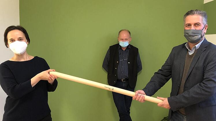 Ulrike Schade (Th&uuml;ringer Verwaltung UNESCO-Biosph&auml;renreservat Rh&ouml;n) hat die Federf&uuml;hrung von Torsten Raab (Hessische Verwaltung) &uuml;bernommen. F&uuml;r die symbolische &Uuml;bergabe haben die Mitarbeiter des Naturparks Hessische Rh&ouml;n eigens einen neuen Coronakonformen Staffelstab angefertigt. Auch der Bayerische Verwaltungsstellenleiter Michael Geier (Mitte) freut sich auf die weitere l&auml;nder&uuml;bergreifende Zusammenarbeit. Foto: Anna-Lena Bieneck