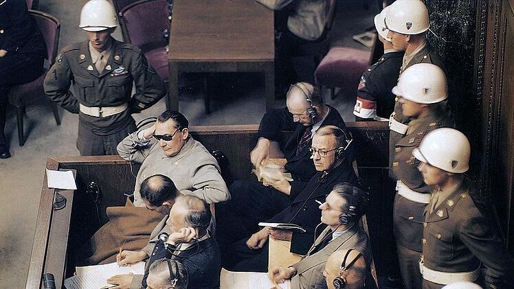 Die NS-Kriegsverbrecher (unter anderem Hermann G&ouml;ring, mit Sonnenbrille) w&auml;hrend des N&uuml;rnberger Prozesses auf der Anklagebank: Per Kopfh&ouml;rer k&ouml;nnen alle Prozessbeteiligten der Simultan&uuml;bersetzung folgen.