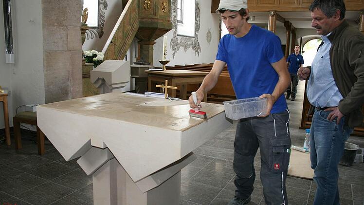 Juniorchef Jens Vey (links) legt letzte Hand an an den neuen Steinaltar an. Kirchenpfleger Hubert Herbert erläutert die Arbeiten. Foto: Gabriele Sell