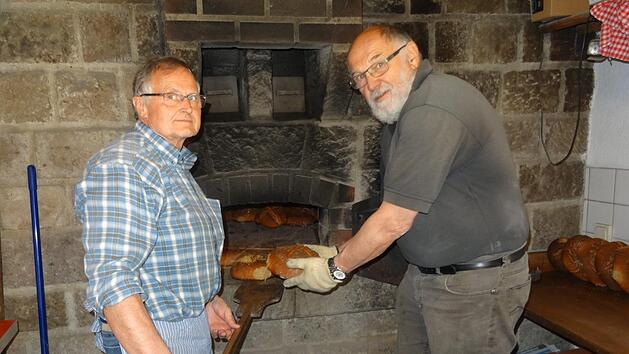 Winfried Bott (links) und Siegfried Wiesner vom Obst- und Gartenbauverein (OGV) Bad Br&uuml;ckenau sch&uuml;rten den Ofen im Backhaus und fertigten den Teig. Foto: Martina Fuchs