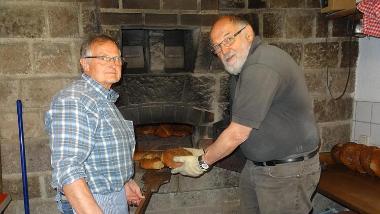 Winfried Bott (links) und Siegfried Wiesner vom Obst- und Gartenbauverein (OGV) Bad Br&uuml;ckenau sch&uuml;rten den Ofen im Backhaus und fertigten den Teig. Foto: Martina Fuchs
