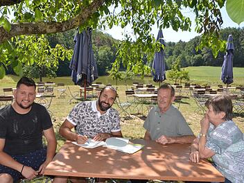 Sami Alijaj unterzeichnet im idyllischen Biergarten den Vertrag. Gemeinsam mit seinem Mitarbeiter Alex Vladulescu (links) hat er das Gasthaus Gumbrecht in Obermembach gepachtet. Hans und Elfriede Gumbrecht freuen sich auf die Nachfolge.  Foto: Bernhard Panzer