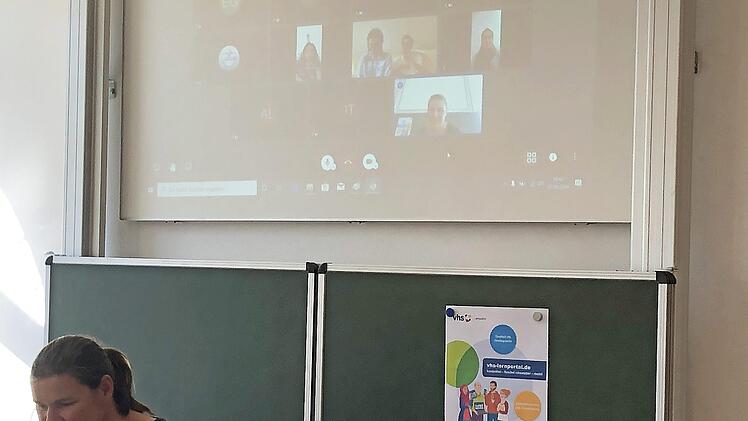 Dozentin Christina Klug sitzt in der Volkshochschule am PC, ihre Schüler (oben) sind ihr per Videokonferenz zugeschaltet.  Fotos: VHS Coburg