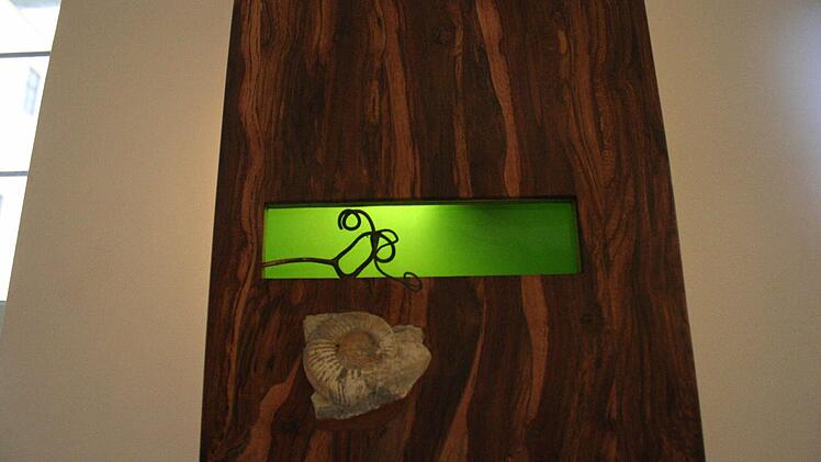 Eine Lampe mit Flaschenglas, Rebholz und einer Versteinerung aus Muschelkalk.