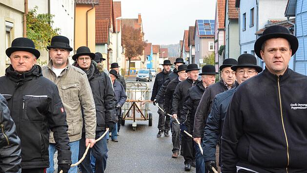 Mit ernster Miene ziehen die Männer der Cocksinnung den Karren mit dem Schwein durch den Ort. Fotos: Björn Hein