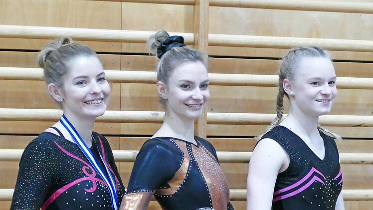 Ernst Weitl (links), der Trainer des TV Ketschendorf, mit kritischem Blick auf seine Turnerin am Stufenbarren. - Gut geturnt (zweites Foto von links): die TVK-Turnerinnen Anna Rogler, Katalin Hauck (2. Platz in der AK 18+) und Lina Zimmermann (Siegerin der AK 14/15). - (Drittes Foto von links): Starker Beginn von Lina Zimmermann beim "Schweizer"-Angang am Balken. - Rechts: Mialotta Peschla, Michelle Moore und Salome Umlauff vom TVK nach der Siegerehrung. Fotos: privat (1)/Ernst Weitl (3)