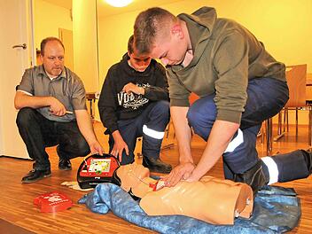 Ein Defibrillator, der Stromschläge verteilt, kann das Leben von  herzkranken Menschen retten. Jürgen Müller vom ZTM (Zentrum für Telemedizin  Bad Kissingen, links) führte in Rannungen ein Gerät vor. Zwei Mitglieder  der Feuerwehr und ein Dummy halfen ihm dabei. Foto: Dieter Britz