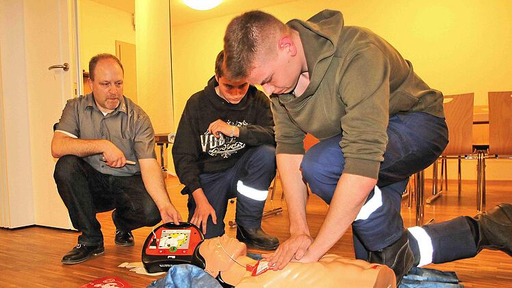 Ein Defibrillator, der Stromschläge verteilt, kann das Leben von  herzkranken Menschen retten. Jürgen Müller vom ZTM (Zentrum für Telemedizin  Bad Kissingen, links) führte in Rannungen ein Gerät vor. Zwei Mitglieder  der Feuerwehr und ein Dummy halfen ihm dabei. Foto: Dieter Britz