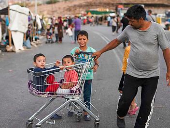 Ein Flüchtling zieht zwei Kinder in einem Einkaufswagen in der Nähe der griechischen Stadt Mytilini. Nach dem Großbrand im Flüchtlingslager Moria auf Lesbos bleibt die Lage auch nach Öffnung erster Ersatz-Unterkünfte angespannt.  Foto: P. Giannakouris/dpa