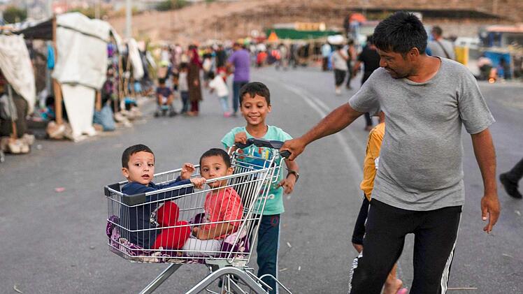 Ein Fl&uuml;chtling zieht zwei Kinder in einem Einkaufswagen in der N&auml;he der griechischen Stadt Mytilini. Nach dem Gro&szlig;brand im Fl&uuml;chtlingslager Moria auf Lesbos bleibt die Lage auch nach &Ouml;ffnung erster Ersatz-Unterk&uuml;nfte angespannt.  Foto: P. Giannakouris/dpa