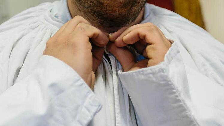 Zuerst legt Scholz das lange, gerade geschnittene, hemdartige Kleid an. Die Albe ist ein ursprünglich römisches Kleidungsstück. Es dient als Untergewand, über dem unterschiedliche liturgische Gewänder getragen werden.