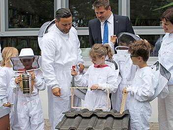 Monique Nickel (Mittagsbetreuung), B&uuml;rgermeister Martin Finzel, Marcel Sagasser (VR-Bank Lichtenfels-Ebern, Gesch&auml;ftsstelle Ahorn) und Gabriele Walther (Direktorin Johann-Gemmer-Grundschule) begutachten zusammen mit den Sch&uuml;lern einige Imker-Utensilien.  Foto: Gemeinde Ahorn