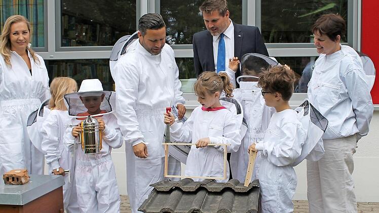 Monique Nickel (Mittagsbetreuung), B&uuml;rgermeister Martin Finzel, Marcel Sagasser (VR-Bank Lichtenfels-Ebern, Gesch&auml;ftsstelle Ahorn) und Gabriele Walther (Direktorin Johann-Gemmer-Grundschule) begutachten zusammen mit den Sch&uuml;lern einige Imker-Utensilien.  Foto: Gemeinde Ahorn