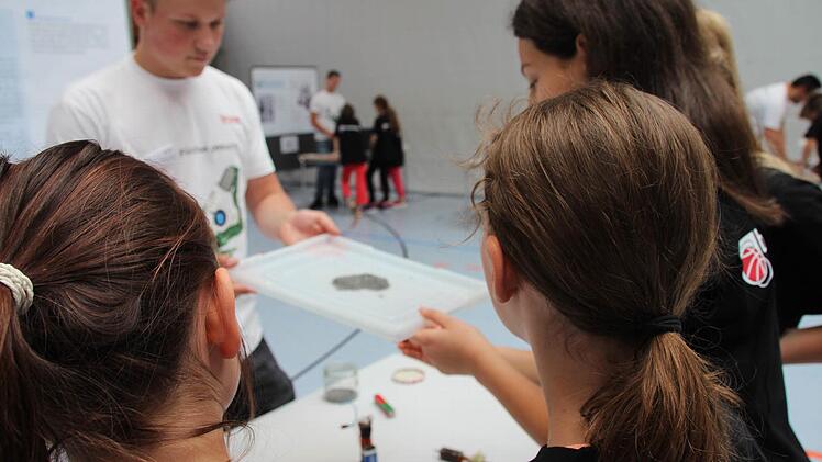 Azubi Cedric Fehn erkl&auml;rt mit Hilfe eines Magneten und Eisensp&auml;nen die Wirkung von Magnetismus. Foto: Fenna Kreuz