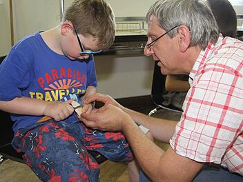 Emil lässt sich von Roland Friedrich die Tricks zeigen. Mit dem Handschnitzmesser schnitzt man immer Richtung Daumen, niemals von sich weg, das wäre zu gefährlich. Fotos: Sonja Adam