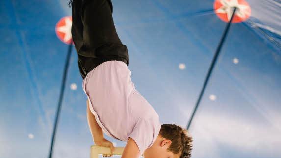 Jordan (11) wärmt sich mit einem Handstand auf dem Stuhl auf.