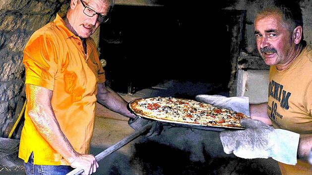 Die Gr&uuml;ndungsmitglieder Karlheinz Gl&uuml;ck und Stefan Hofbauer stehen f&uuml;nf Stunden lang an den beiden Holz&ouml;fen und erf&uuml;llen ihren hei&szlig;en Ehrendienst. Fort: Gerd Schaar