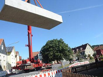Über Baumwipfel und Häuserdächer hinweg wurden die Betonfertigteile für die Brücke zentimetergenau in das Bachbett gehievt. Das Fließbecken des Durchlasses wiegt 47,6 Tonnen und ist an den Seitenwänden circa zwei Meter hoch.K.-H. Hofmann