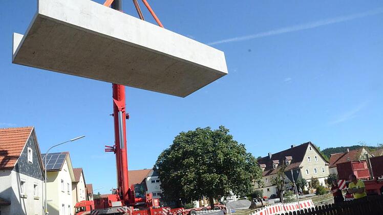 Über Baumwipfel und Häuserdächer hinweg wurden die Betonfertigteile für die Brücke zentimetergenau in das Bachbett gehievt. Das Fließbecken des Durchlasses wiegt 47,6 Tonnen und ist an den Seitenwänden circa zwei Meter hoch.K.-H. Hofmann
