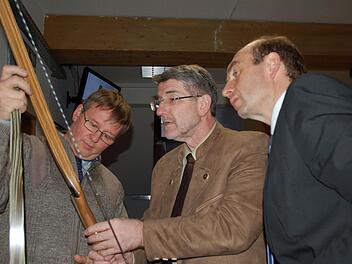 Ein Bogen wird, ähnlich wie ein Ski, aus verschiedenen Schichten gefertigt, die Uwe Beier (links) Landrat Michael Busch und Wirtschaftsförderer Martin Schmitz (rechts) genau erklärt. Fotos: Rainer lutz