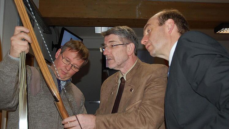 Ein Bogen wird, ähnlich wie ein Ski, aus verschiedenen Schichten gefertigt, die Uwe Beier (links) Landrat Michael Busch und Wirtschaftsförderer Martin Schmitz (rechts) genau erklärt. Fotos: Rainer lutz