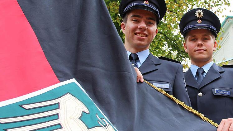 Felix Hollender mit der Hand an der Fahne und Robin Hartmann haben im September ihre Ausbildung bei der Bundespolizei in Oerlenbach begonnen.