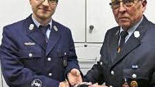 Der langjährige Vorsitzende des Feuerwehrvereins, Emil Lauterbach, übergibt das Mützenband an seinen Nachfolger André Stöcker.
