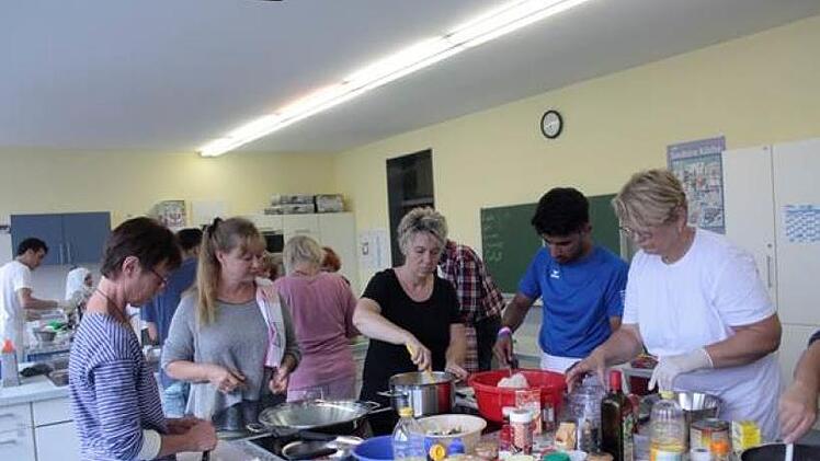 Beim gemeinsamen Kochen in der Kronacher Berufsschule herrschte volle Konzentration. Dennoch war auch Zeit f&uuml;r gemeinsames Singen, Lachen und Austauschen.  Fotos: Heike Sch&uuml;lein