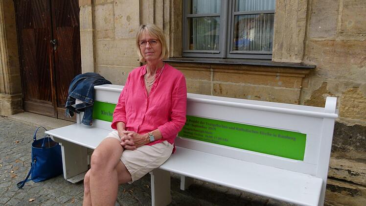 Projektleiterin Susanne Röhner lädt auf die Kirchenbank am Kranen ein.       Foto: Marion Krüger-Hundrup