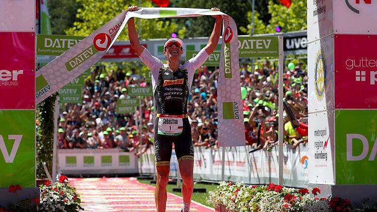 Nach 3,8 km schwimmen, 180 km mit dem Rad und 42 km laufen reckt Sebastian Kienle das Zielbanner in die Luft. Kienle gewann nach zwei zweiten Plätzen in Roth erstmals den Sieg bei der Challenge in Mittelfranken. Foto: Daniel Karmann/dpa