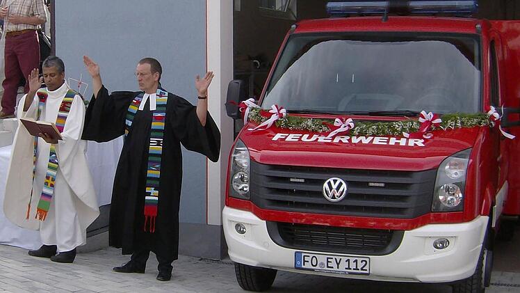 Kaplan Jimmy (l.) und Pfarrer Ulrich Hardt spenden in Dorfhaus dem neuen Feuerwehrauto ihren Segen. Fotos: Malbrich