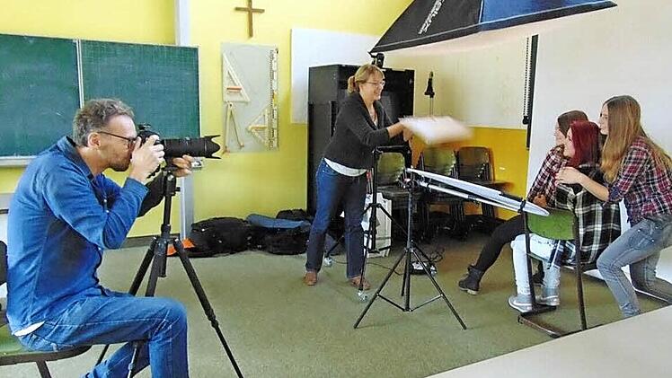 Fotograf Michael Schobe macht Porträtaufnahmen von Sarah Forster, Adriana Marsing und Laura Siebenhaar. Christiane Arndt fächert den Mädchen mit einem Stück Pappe ein bisschen Luft zu. Fotos: Petra Malbrich