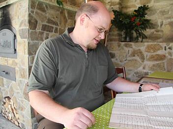 Hans Pezold hält die Familientradition in Ehren und stöbert gerne in den historischen Fundstücken, selbst der Kaufvertrag für das Anwesen ist noch vorhanden. "Man kann die Grundstücke genau an den Flurnummern erkennen. Die haben sich nicht geändert", ist Hans Pezold begeistert. Fotos: Sonja Adam