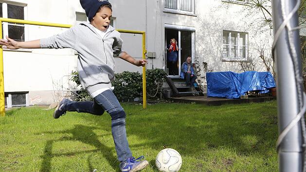 Mutter Ricarda und Opa Norbert schauen Lian beim Kicken im Garten zu. Foto: Matthias Hoch