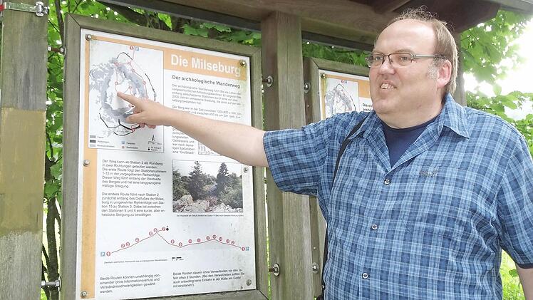 Archäologe Frank Verse mit einer Tafel, die auf die Geschichte der Milseburg-Besiedelung eingeht.