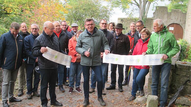 Mit dem Zerschneiden des Bandes eröffnete Bürgermeister Armin Warmuth (Mitte), Sprecher von Frankens Saalestück und die Vize-Bürgermeister von Gemünden, Werner Herrbach (links) und Bad Kissingen, Richard Fix (rrechts) den neuen Wein- und Genusswanderweg vor den Toren der Trimburg.