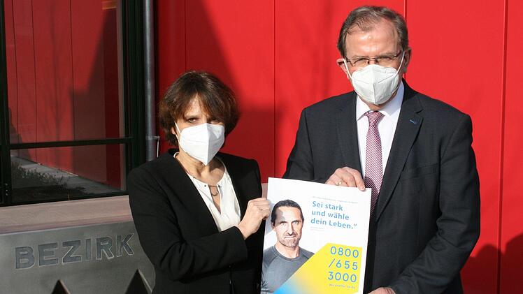 "Sei stark und wähle dein Leben." Mit diesem Satz wirbt der bekannte Extrembergsteiger Alexander Huber für die Krisendienste, die die bayerischen Bezirke jetzt auf den Weg bringen. Das Foto zeigt Bezirkstagspräsident Erwin Dotzel und die Verantwortliche für die Leitstelle des Krisennetzwerks Unterfranken, Dr. med. Simona Kralik. Foto: Markus Mauritz