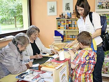 Antje Rink kommt mit Sohn Dominik regelmäßig zur Buchausleihe in die Familienbücherei. Monika Neiber und Emmi Hoffmann gehören zum Helferteam, die die kleine Leihbücherei ehrenamtlich am laufen halten. Fotos: Heike Beudert