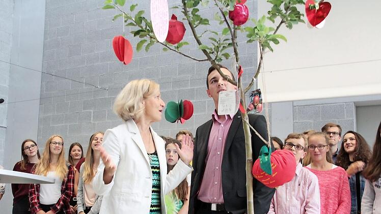 Fassungslos steht Liselotte Rall vor dem Apfelbäumchen, dass ihr Schülersprecher Nico Kaupert, umringt von der Gottesdienstband, auf der Bühne der Aula überreicht.  Fotos: Andreas Oswald