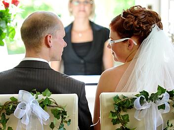 Ein junges Hochzeitspaar schaut sich während seiner Trauung vor der Standesbeamtin an.  Foto: Patrick Pleul, dpa