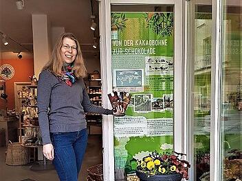 Sabine Allmendiger vom Weltladen in der Wiesentstra&szlig;e in Forchheim vor dem Veranstaltungsplakat &bdquo;Von der Kakaobohne zur Schokolade&ldquo;