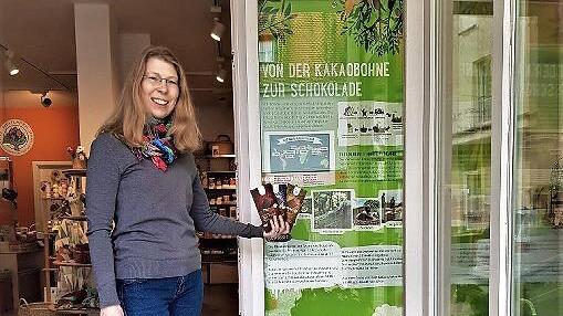 Sabine Allmendiger vom Weltladen in der Wiesentstra&szlig;e in Forchheim vor dem Veranstaltungsplakat &bdquo;Von der Kakaobohne zur Schokolade&ldquo;