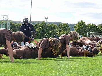 Bilal Afrane, Trainer in der Fußbalschule des FC St. Pauli, lässt die Kinder im Sportpark eine Liegestütz-Übung machen, die nur funktioniert, wenn alle mitmachen. Foto: Jürgen Schmitt
